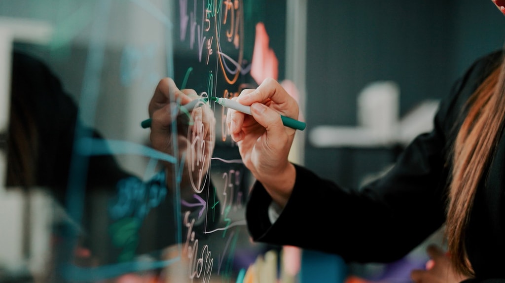 close up of person taking notes on a transparent wall panel