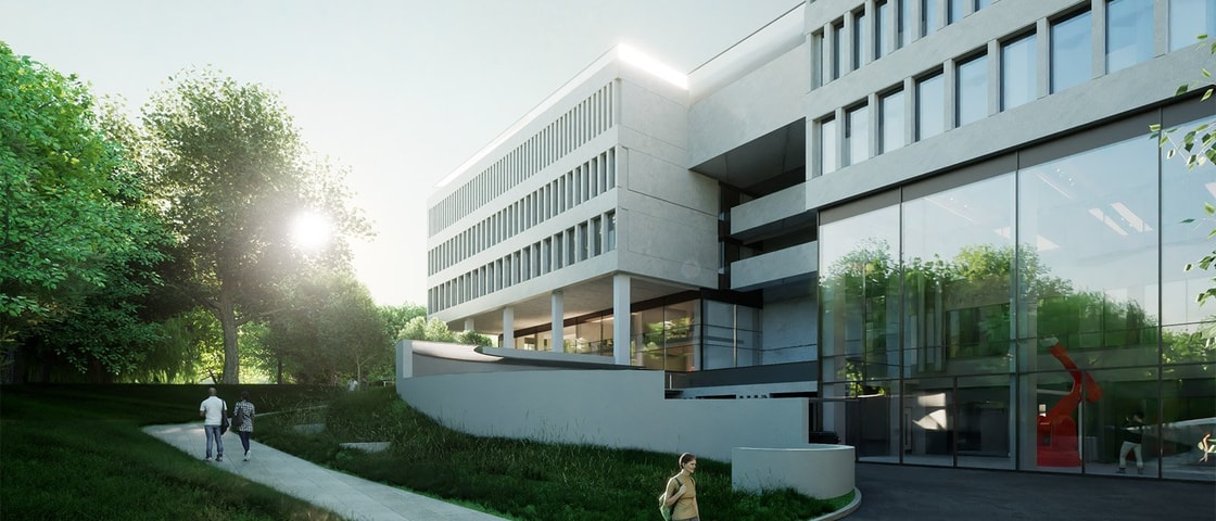 Modern building with large glass windows, surrounded by greenery, as people walk along a pathway in the serene morning light.
