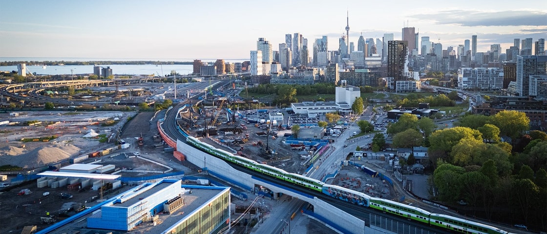 Aerial view of a cityscape featuring a train traveling along the tracks amidst buildings and streets below.