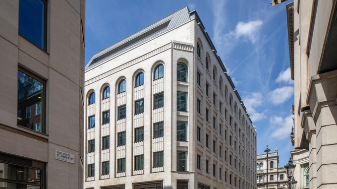 30 Duke Street office building in London, featuring a light stone façade, arched windows and a metal roof, viewed from street level on a sunny day.