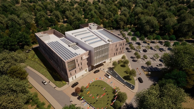 Aerial view of the European Centre for Medium-Range Weather Forecasts (ECMWF) Headquarters, featuring a modern building with solar panels, surrounding greenery, and a circular display of international flags at the entrance.