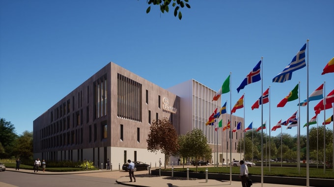 Exterior view of the European Centre for Medium-Range Weather Forecasts (ECMWF) Headquarters, showing a modern building with vertical windows and a row of international flags along the entrance pathway.