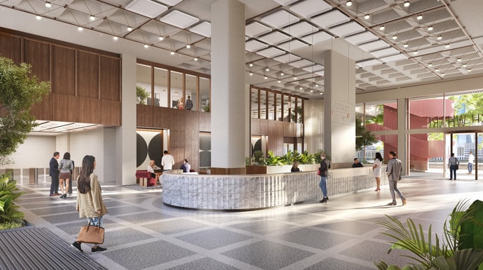 A CGI rendering of a contemporary office reception and lobby space with a double-height ceiling, large structural columns and extensive glazing. The interior features a curved stone reception desk surrounded by planting, timber wall finishes and seating areas. Several people are visible throughout the lobby, while large entrance doors open onto an external terrace. The words "Fresh Wharf" are displayed on a feature wall beside the reception area, and natural daylight fills the space through floor-to-ceiling windows.