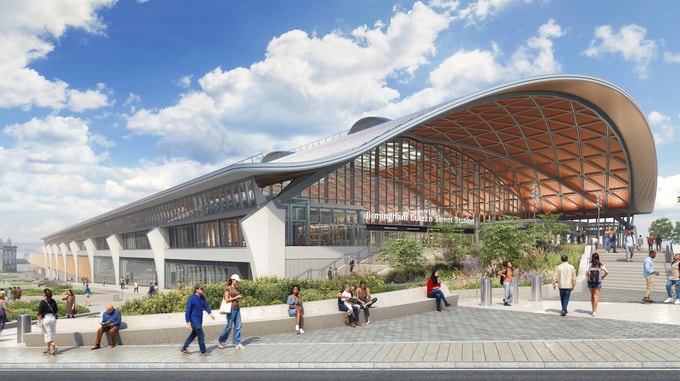 Architectural rendering of the HS2 Curzon Street station, showing a large curved roof with a timber-lined underside, expansive glass façade, and landscaped public plaza in the foreground where several people are walking and sitting.