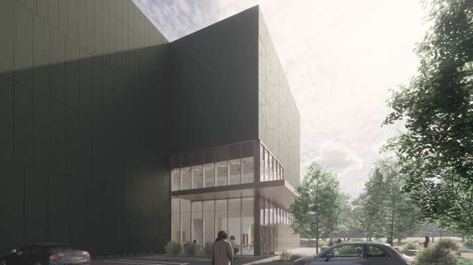 Exterior view of the Natural History Museum, showcasing a modern building with a tall dark green facade featuring circular patterns, large glass windows revealing a bright interior, landscaped greenery, and people walking under a clear sky.