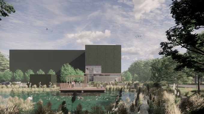 View of the Natural History Museum project featuring a modern dark green building behind a landscaped pond with a wooden deck and people enjoying the outdoor space