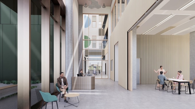 Interior view of the Natural History Museum project showing a bright, modern lobby with tall windows, a reception desk, seating area, and people working and conversing.