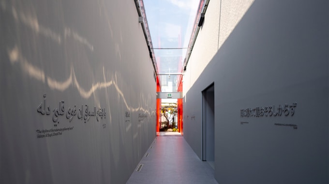 Interior of building hallway with glass ceiling lined with Japanese and Arabic text.