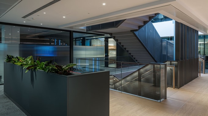 Taylor Wessing corridor featuring layered timber ceiling panels, curved architectural walls, and ambient lighting that creates a warm, flowing transition through the space.