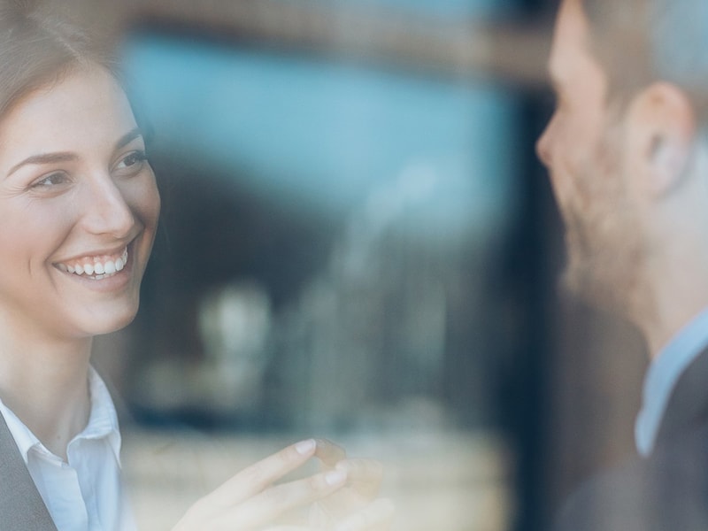 Closeup of two people have a meeting viewed from the other side of glass wall