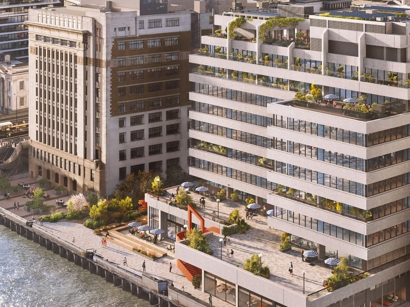 A CGI aerial rendering of a contemporary riverside office development alongside the River Thames in London. The stepped building features extensive floor-to-ceiling glazing, landscaped terraces, rooftop gardens and outdoor seating areas. A large waterfront plaza with planting, trees and public seating overlooks a pedestrian promenade running along the river’s edge. Several people are visible throughout the public spaces, while neighbouring city buildings and a bridge span the water in the background.