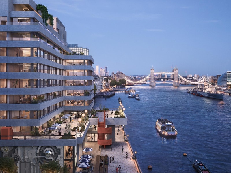 A CGI architectural rendering of a modern riverside building overlooking the River Thames at dusk. The multi-storey development features large glazed windows, stepped terraces, rooftop planting and active waterfront spaces with outdoor seating and pedestrians. Tower Bridge is illuminated in the background, while several boats travel along the river, framed by the London skyline under a blue evening sky.