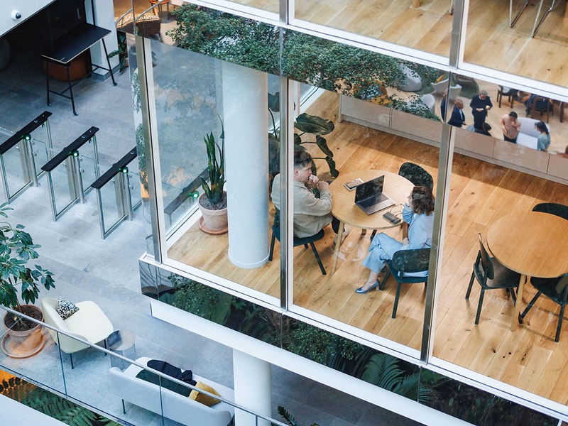 two colleagues having a meeting in a corner class meeting room overlooking a large atrium 